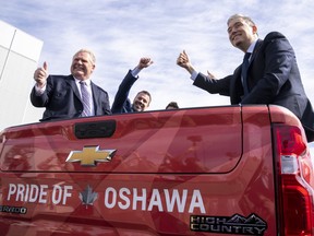 Ontario Premier Doug Ford, left, and federal Minister of Innovation, Science and Industry François-Philippe Champagne, right sit in the back of a pickup truck at GM Canada’s Canadian Technical Centre, in Oshawa, in April.