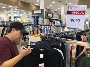 A customer checks price tags as she shops at a retail store in Schaumburg, Ill., Thursday, June 30, 2022.