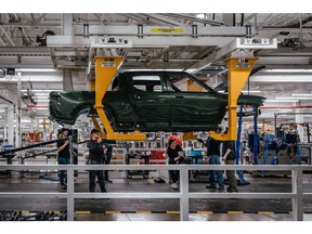 Workers assembly components of a Rivian R1T electric vehicle (EV) pickup truck at the company's manufacturing facility in Normal, Illinois, US., on Monday, April 11, 2022. Rivian Automotive Inc.?produced 2,553 vehicles in the first quarter as the maker of plug-in trucks contended with a snarled supply chain and pandemic challenges.