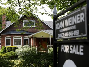 A realtor's sign stands outside a house for sale in Toronto.