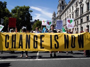 Demonstrators hold placards and banners as they take part in a protest march arriving in Parliament Square, in London, on July 23, 2022 to demand action over the cost of living crisis and the climate change crisis.
