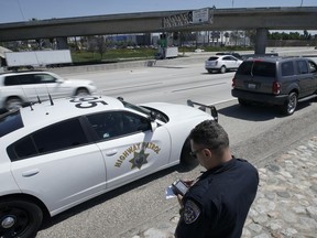 FILE - California Highway Patrol officer Troy Christensen runs a driver's license after stopping a motorist along Interstate 5 who was suspected of speeding on April 23, 2021, in Anaheim, Calif. The U.S. government's road safety agency said Tuesday, July 19, 2022, that it will spend $8 million on ads aimed at stemming the rising number of traffic deaths caused by speeding.