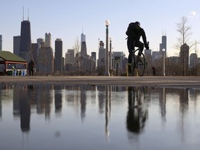 FILE - The Chicago skyline is reflected in the water of the thawed snow as a cyclist passes by at North Avenue Beach on March 1, 2021, in Chicago. According to a study, a nearly 80-year-old law intended to put distressed and tax-delinquent Chicago-area properties back to productive use has done little to improve or solve racial inequities in the city's Black and Latino neighborhoods. A report released Tuesday, July 19, 2022, by the Cook County treasurer's office proposes scrapping or modifying Illinois' Scavenger Sale law in favor of tax-cutting and other programs that may allow homeowners of color to accumulate generational wealth.