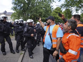 Police officers are pushed back by demonstrators after the arrest of a participant in a demonstration of port workers in front of the union building in the city center in Hamburg, Germany, Friday, July 15, 2022. Several participants were injured in a brief confrontation between participants and police.