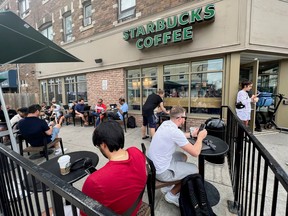 People crowd around a Starbucks coffee shop to use its free wifi on the Bell network, during a major outage of Rogers Communications' mobile and internet networks in Toronto, on July 8, 2022.