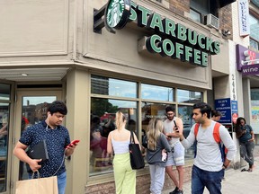 People crowd around a Starbucks coffee shop to use its free wifi on the Bell network, during a major outage of Rogers Communications' mobile and internet networks.