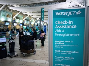WestJet Airlines says a system outage Thursday morning is delaying some flights and intermittently impacting the company's operations. A Westjet employee assists people checking in for a domestic flight at Vancouver International Airport, in Richmond, B.C., on Thursday, January 21, 2021.