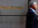 Ein Mann geht die Wall Street in New York entlang.