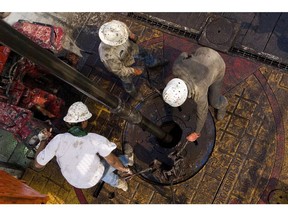 Floorhands move a drill pipe collar as pipe is removed from a natural gas well being drilled in the Eagle Ford shale in Karnes County, Texas. Photographer: Eddie Seal