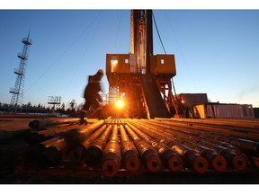 A worker passes an illuminated oil drilling rig, operated by Rosneft PJSC, in the Samotlor oilfield near Nizhnevartovsk, Russia, on Tuesday, March 21, 2017. Russia's largest oil field, so far past its prime that it now pumps almost 20 times more water than crude, could be on the verge of gushing profits again for Rosneft PJSC. Photographer: Andrey Rudakov/Bloomberg