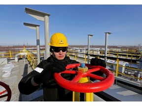 A worker turns a flow valve near oil storage tanks at a pumping station, operated by Rosneft PJSC, in the Samotlor oilfield near Nizhnevartovsk, Russia, on Monday, March 20, 2017. Russia's largest oil field, so far past its prime that it now pumps almost 20 times more water than crude, could be on the verge of gushing profits again for Rosneft PJSC.