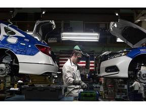 A production associate adjusts his hat while working between 2018 Honda Accord vehicles during production at the Honda of America Manufacturing Inc. Marysville Auto Plant in Marysville, Ohio, U.S., on Thursday, Dec. 21, 2017. More than three decades after Honda Motor Co. first built an Accord sedan at its Marysville factory in 1982, humans are still an integral part of the assembly process -- and that's unlikely to change anytime soon. Photographer: Ty Wright/Bloomberg