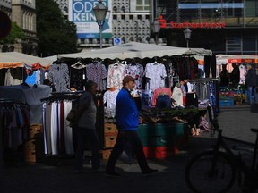 Shoppers pass a clothes market stall near a Stadtsparkasse bank branch in Magdeburg, Germany, on Thursday, May 28, 2020. German Chancellor Angela Merkel's government is preparing a bundle of measures to put Europe's largest economy back on track after a nosedive triggered by the coronavirus pandemic. Photographer: Krisztian Bocsi/Bloomberg