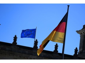 A German national flag and a European Union (EU) flag fly above the Bundestag in Berlin, Germany, on Wednesday, Sept. 9, 2020. Germany plans significant new borrowing next year to fuel the recovery of Europe's largest economy from the fallout of the coronavirus and may continue to rely on debt spending in the future. Photographer: Krisztian Bocsi/Bloomberg
