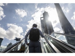 A morning commuter rides an escalator in the Lujiazui Financial District in Shanghai, China, on Friday, Oct. 9, 2020. China's yuan strengthened and stocks rose on mainland exchanges in a positive start to the month for traders returning to work after an eight-day holiday.