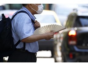 A pedestrian holding a folding fan in the Marunouchi district of Tokyo, Japan, on Friday, July 1, 2022. The government issued a heat stroke alert for several regions in the country including the nation's capital, urging people to take health precautions amid scorching temperatures.