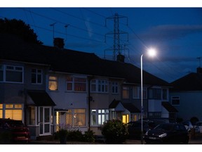 An electricity transmission tower near residential houses with lights on in Upminster, UK, on Monday, July 4, 2022. The UK is set to water down one of its key climate change policies as it battles soaring energy prices that have contributed to a cost-of-living crisis for millions of consumers.
