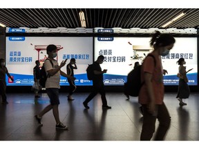 Commuters walk past an advertisement for Ant Group Co.'s payments app Alipay at a subway station in Shanghai, China. Photographer: Qilai Shen/Bloomberg