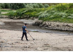 A man searches the exposed bed of the Rhine with a metal detector in Lobith, Netherlands, on July 30. Photographer: Peter Boer/Bloomberg