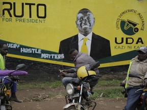 Kenyan Boda Boda motor cycle riders wait near a large mural of William Ruto, a contesting bid for president, in Eldoret, Kenya, Friday, Aug.12, 2022. Kenyans are waiting for the results of a close presidential election in which the turnout was lower than usual.