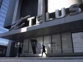 A woman walks in front of the Telus head office is shown in Toronto on Thursday, February 11, 2021. Telus Corp. wants to pass on credit card fees to customers, and plans to tack on a 1.5 per cent "processing fee" starting this fall.