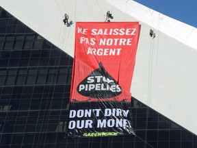Greenpeace activists hang a banner from Olympic Stadium in Montreal, Thursday, July 19, 2018, protesting Canada's Trans Mountain pipeline expansion. A new report from Greenpeace warns that Canada's biggest banks could be pushed out of a UN-backed net-zero emission coalition if they don't boost their climate commitments.