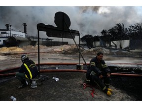 Firefighters rest in the area where the massive fire at a fuel depot sparked by a lightning strike occurred in Matanzas, Cuba, on August 9, 2022.  Photographer: Yamil Lage/AFP/Getty Images