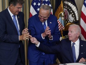 President Joe Biden hands the pen he used to sign the Democrats' landmark climate change and health care bill to Sen. Joe Manchin, D-W.Va., as Senate Majority Leader Chuck Schumer of N.Y., watches in the State Dining Room of the White House in Washington, Tuesday, Aug. 16, 2022.