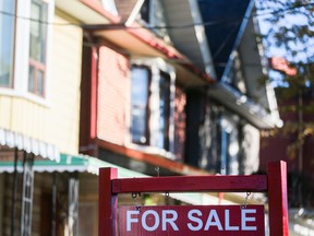 A for sale sign is displayed in front of a house in the Riverdale area of Toronto on Wednesday, September 29, 2021. As the country's real estate market cools, the Canadian Real Estate Association is expected to release home sales figures for July.