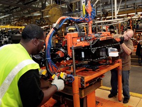 Ford assembly workers install a battery onto the chassis of an electric vehicle in Michigan.
