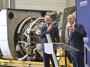 German Chancellor Olaf Scholz, right, stands besides Christian Bruch, CEO of Siemens Energy, at the turbine serviced in Canada for the Nordstream 1 natural gas pipeline in Muelheim an der Ruhr, Germany, Aug. 3, 2022. German Chancellor Olaf Scholz visited a plant by Siemens Energy where a turbine, which is at the center of a dispute between Germany and Russia over reduced gas supplies, is currently sitting in storage until it can be shipped to Russia.