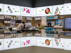 An employee assists a customer at a Telus Corp. store in Toronto.