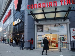 Customers stand in line for curb-side pickup at a Canadian Tire Corp. store in Toronto.