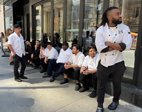 Kitchen staff wait outside a restaurant during an electricity power outage in Toronto.