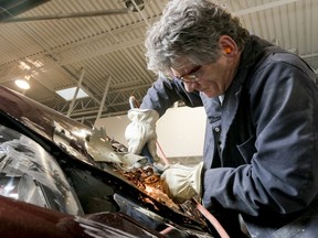 A collision technician works on a crunched car at Feliks Auto Body in Calgary.
