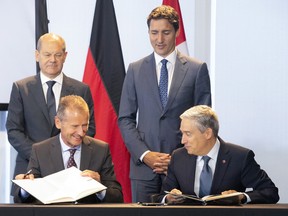 Herbert Diess, CEO and chairman of the board of management at Volkswagen AG, bottom left, and Innovation Minister François-Philippe Champagne, bottom right, sign an agreement as Prime Minister Justin Trudeau, top right, and German Chancellor Olaf Scholz look on at an event in Toronto.