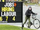 A woman checks out a jobs advertisement sign during the COVID-19 pandemic in Toronto.