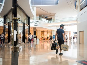 Un comprador sale de una tienda con varias bolsas de compras en el Sherway Gardens Centre de Toronto.