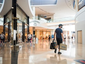 A shopper exits a store holding multiple shopping bags in Sherway Gardens mall in Toronto.