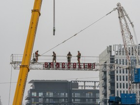 Construction workers assemble a crane high in the air in Toronto.