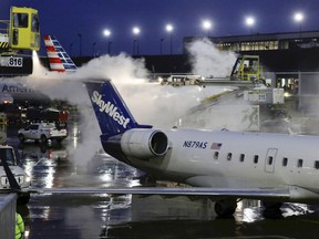 FILE - A deicing agent is applied to a SkyWest airplane before its takeoff on Jan. 18, 2019, at O'Hare International Airport in Chicago. The federal government filed a lawsuit against the airline, Wednesday, Aug. 17, 2022, on behalf of a former employee who says co-workers sexually harassed her, including asking her for sex and making explicit comments about rape in her presence.