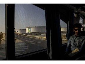 A bus transports employees past crude oil storage tanks in the Juaymah tank farm at Saudi Aramco's Ras Tanura oil refinery and terminal in Ras Tanura, Saudi Arabia. Photographer:  Simon Dawson/Bloomberg