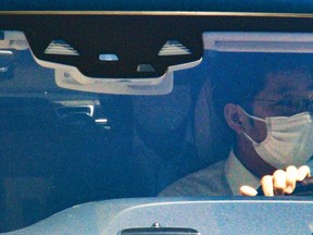 Haruyuki Takahashi, a former Tokyo Olympic organizing committee board member, rides on the back seats of a car as he leaves his home in Tokyo Wednesday, Aug. 17, 2022. Takahashi and three people from a clothing company that was a surprise sponsor of the 2020 Games were arrested on bribery suspicions Wednesday. (Kyodo News via AP)