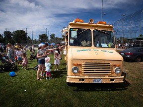 People purchase ice cream from one of Meedo Falou's Rainbow Ice Cream trucks, in Tsawwassen, B.C., on Monday, August 1, 2022. Much of Canada has been sweltering, but that's cold comfort for ice cream truck vendors like Falou, who says inflation and high fuel costs are melting away his profits.