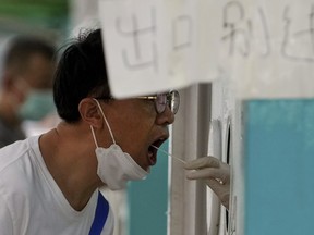 A resident gets his routine throat swabs at a COVID-19 testing site in Beijing, Sunday, Aug. 7, 2022.