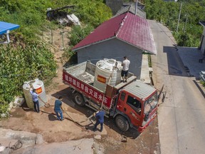 In this photo released by Xinhua News Agency, workers transfer water from a drought relief water truck to residents in Luoping village of Wushan County in southwestern China's Chongqing, Saturday, Aug. 13, 2022. Unusually high temperatures and a prolonged drought are affecting large swaths of China, affecting crop yields and drinking water supplies for thousands of people.