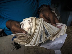 FILE - A worker shows a wad of Cuban pesos in Havana, Cuba, Dec. 11, 2020. The government announced on Aug. 1, 2022 that it will start buying U.S. dollars at an exchange rate five times higher than the official rate, at 110 Cuban pesos per dollar after commission, in an attempt to capture more foreign currency and at the same time combat the informal market.