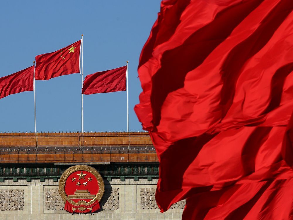 Red flags flutter in the wind near the Chinese national emblem outside the Great Hall of the People in Beijing.