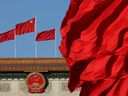 Red flags flutter in the wind near the Chinese national emblem outside the Great Hall of the People in Beijing.