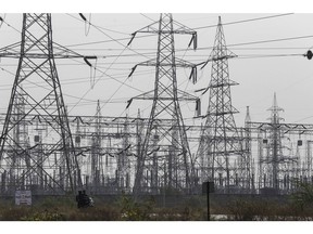 A motorcyclist rides near a sub-station and electricity transmission pylons operated by Maharashtra State Electricity Distribution Co. (MSEDCL) in Nandurbar district, Maharashtra, India, on Wednesday, Jan. 18, 2017. Indian Prime Minister Narendra Modi pledged to bring reliable power to all citizens during the campaign that propelled him into office in 2014, the same year the World Bank pegged India as home to the world's largest un-electrified population. While his government has made progress meeting its 2019 deadline, many families are still missing out, holding back some of India's poorest, most-vulnerable citizens and preventing the country from achieving its development ambitions.
